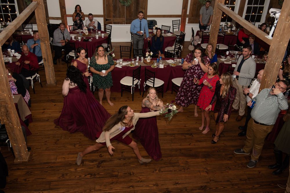 Wedding reception celebration with dramatic dip dance move on rustic wooden dance floor.