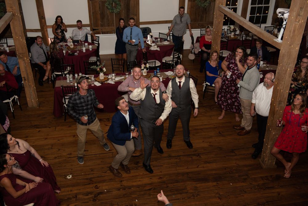 Wedding guests dance together on a rustic wooden dance floor during a reception celebration.