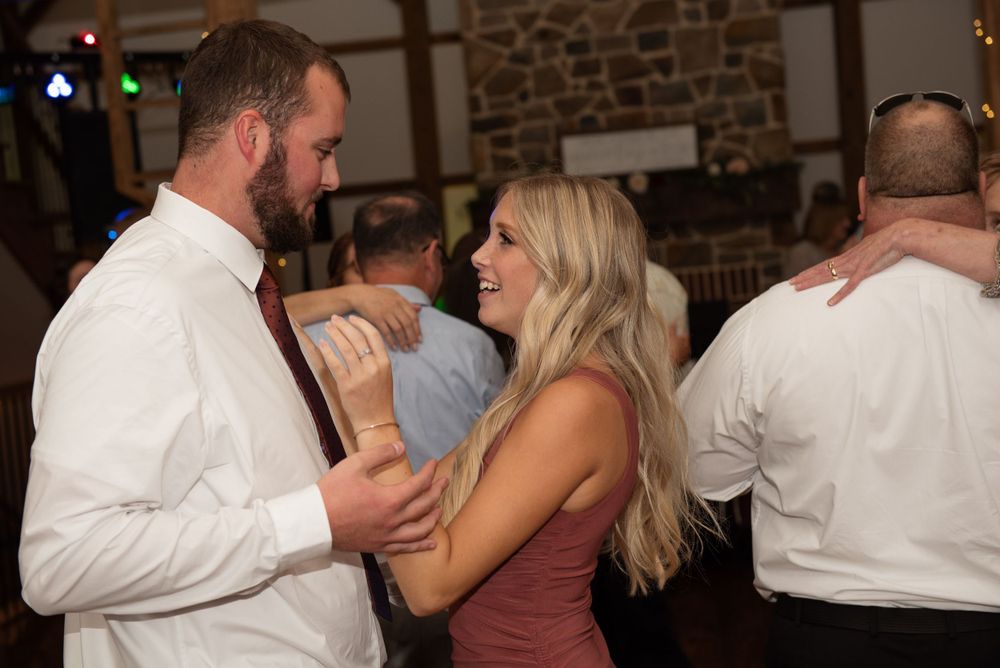 Couples dance together during an evening wedding reception in a rustic stone-walled venue.