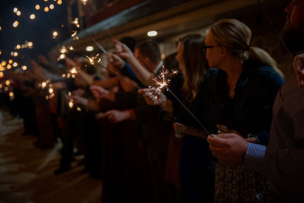Wedding guests hold sparklers creating a magical nighttime celebration atmosphere.