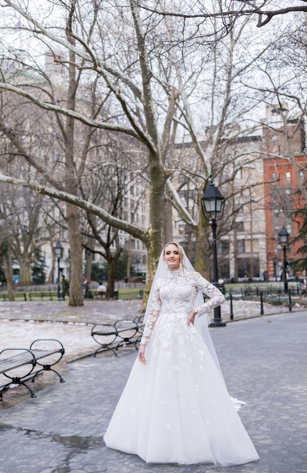 Winter wedding photo in Washington Square Park featuring a full lace gown with long sleeves.