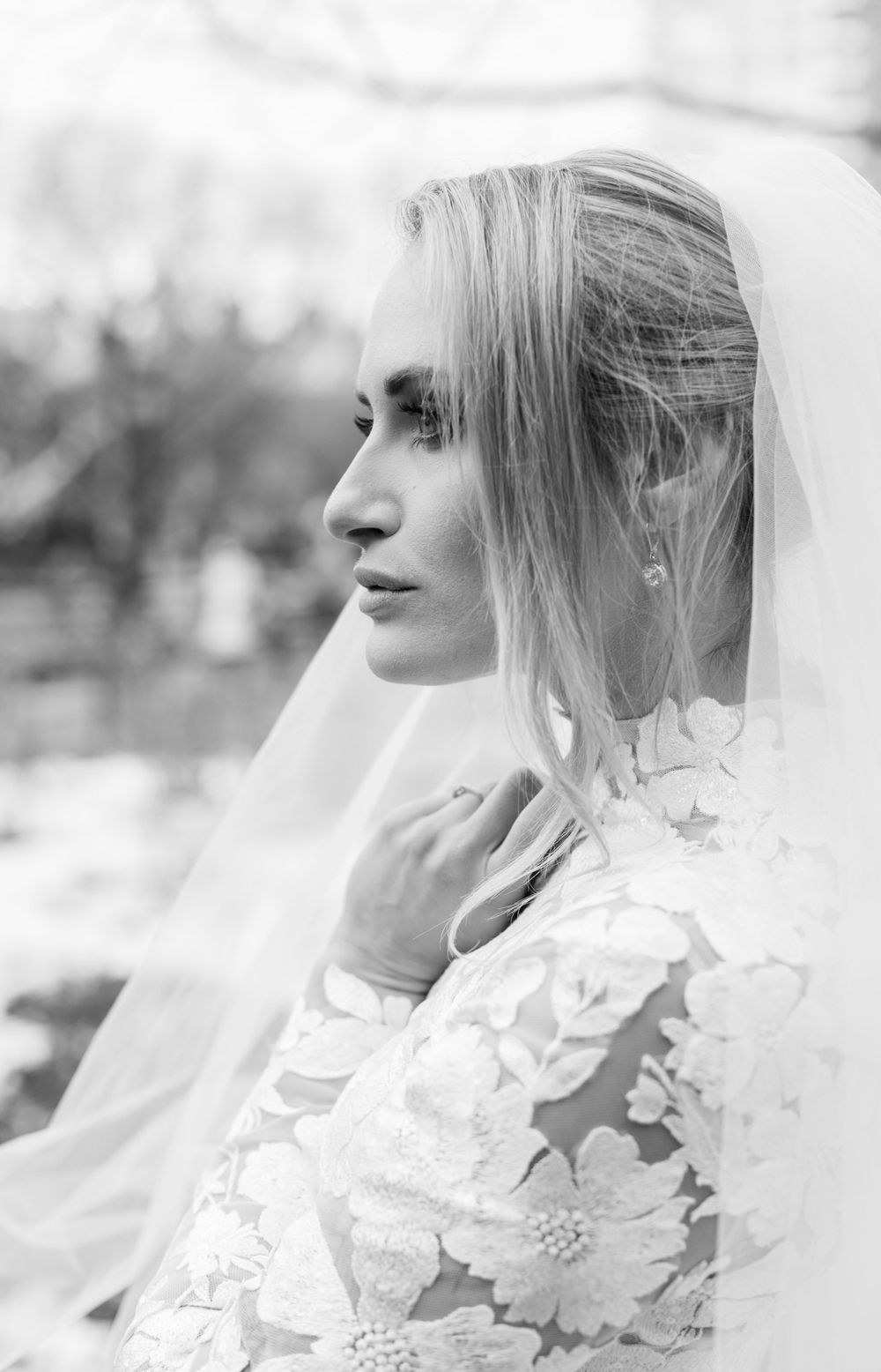 Side profile black and white bridal portrait highlighting intricate lace details and flowing veil.