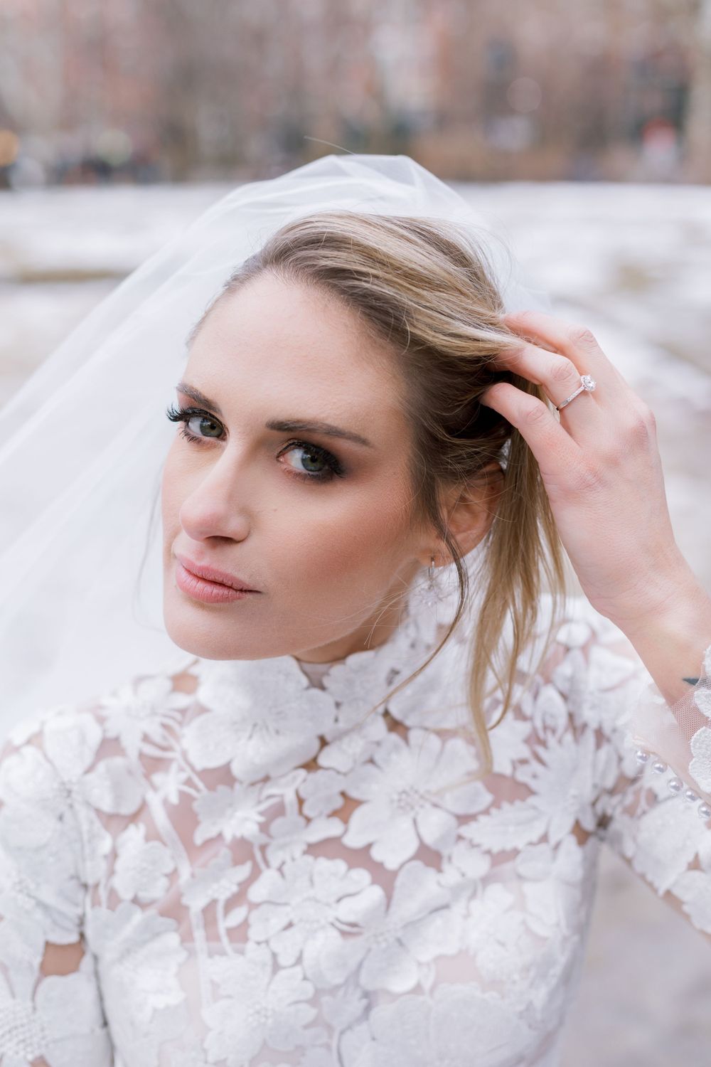 Elegant bridal portrait showcasing intricate lace details and a flowing veil against a winter backdrop.
