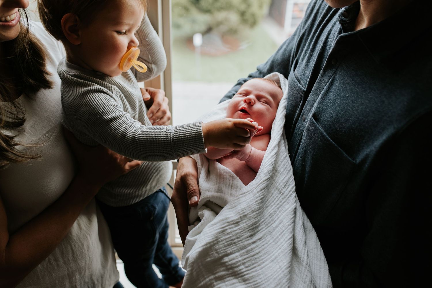 Toddler holding newborn sister's hand