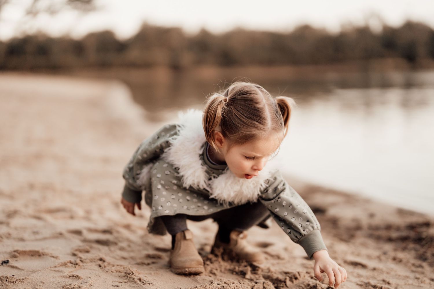 Sepia-toned photo of baby crawling on sandy surface in natural lighting.