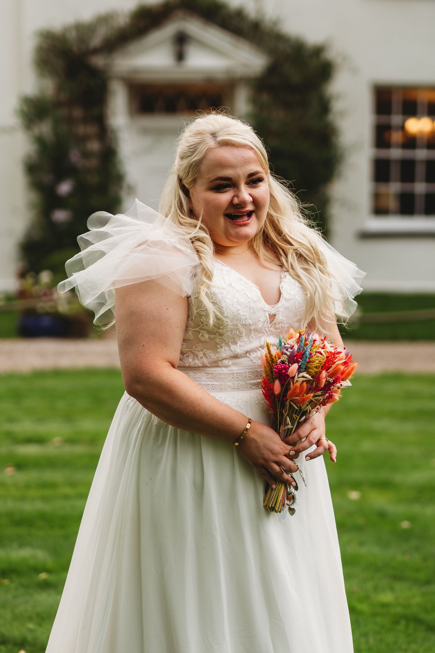 Bride in white wedding dress holding vibrant autumn bouquet outdoors.