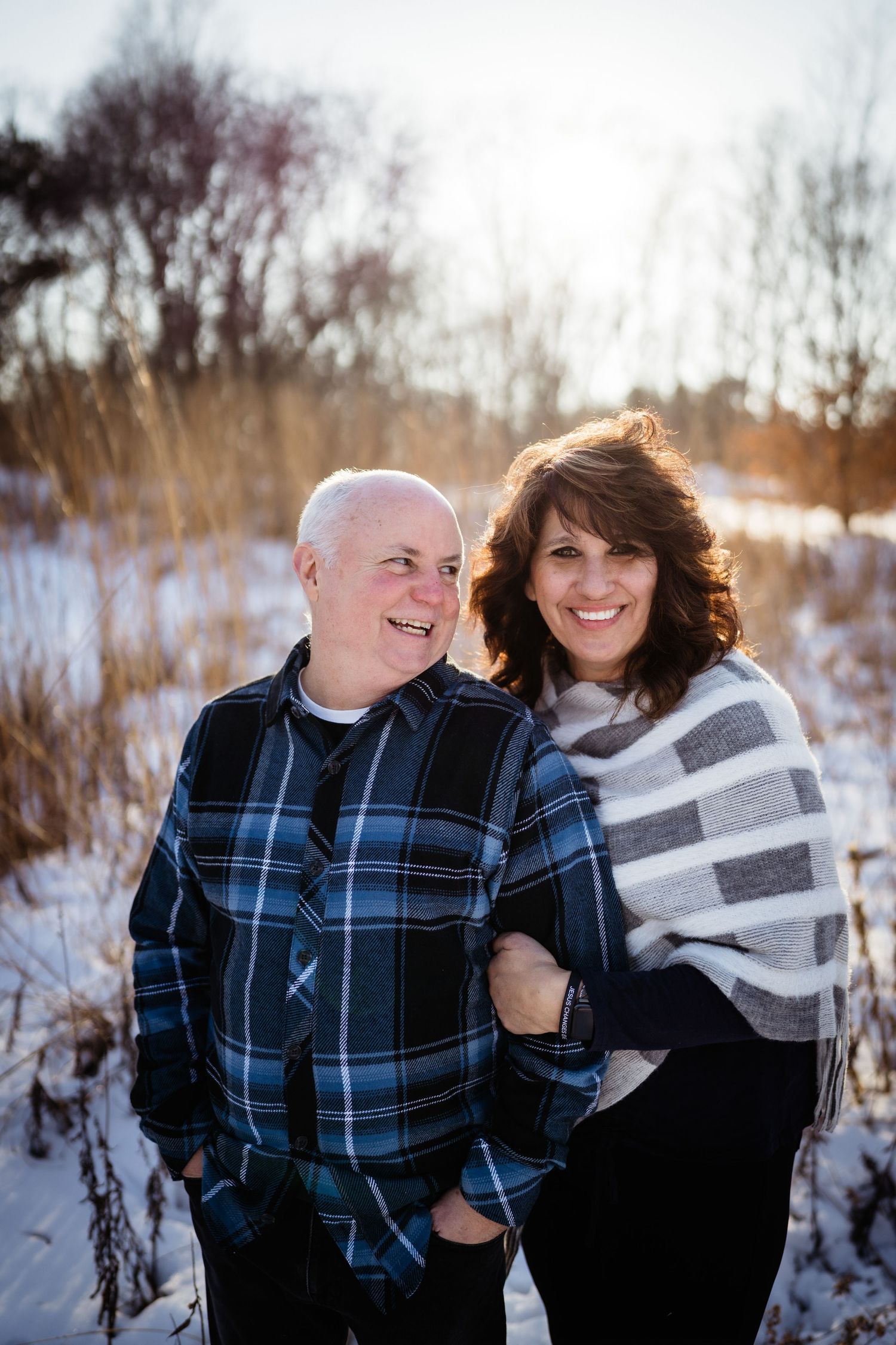 Couple in matching plaid and stripes share intimate moment in winter landscape.