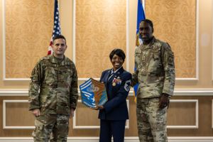 Military personnel and civilians gather for a formal ceremony in an elegant meeting room.