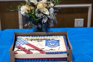 Decorated cakes and floral arrangements displayed on a blue tablecloth at a military event.