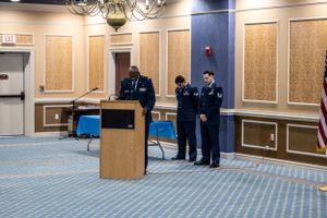 Wide view of a formal military ceremony in a hotel conference room.