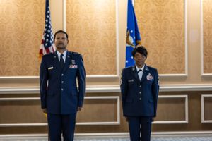 Military personnel stand at attention during an official ceremony in an elegant conference room.