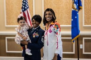 Military ceremony participants pose together in front of American and Air Force flags.