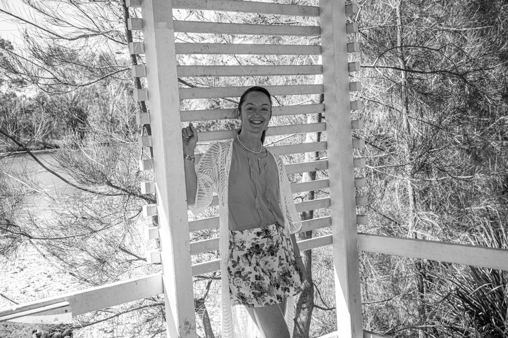 Black and white portrait in gazebo with natural light filtering through slatted walls.