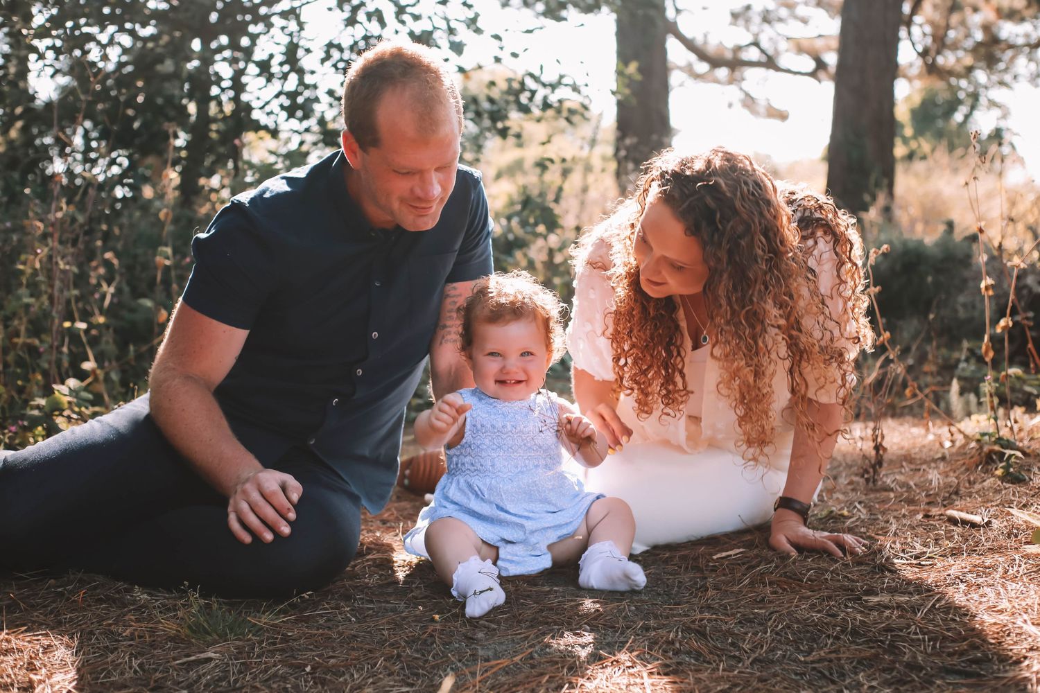 Family sharing intimate moment outdoors in wooded setting.
