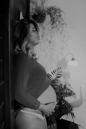 Black and white artistic maternity portrait with indoor lighting.
