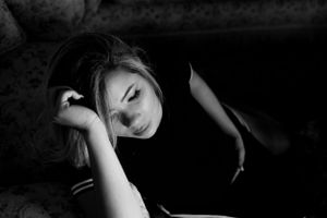 Artistic black and white portrait showing contemplative pose in dark setting.