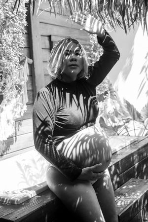 Black and white outdoor maternity photo with dramatic shadow patterns.