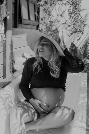 Black and white photo of person reclining on outdoor furniture with natural light.