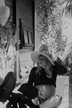 Artistic black and white portrait with shadows and foliage in outdoor setting.