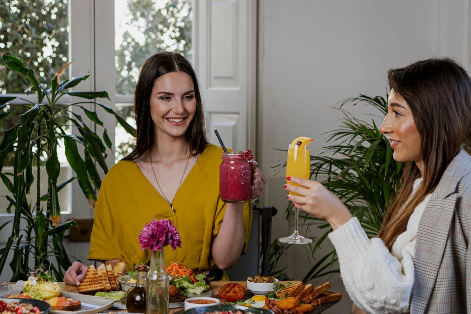 Photo portrait commercial pour un restaurant, deux femmes en train de bruncher en tenant un jus de fruit dans la main.