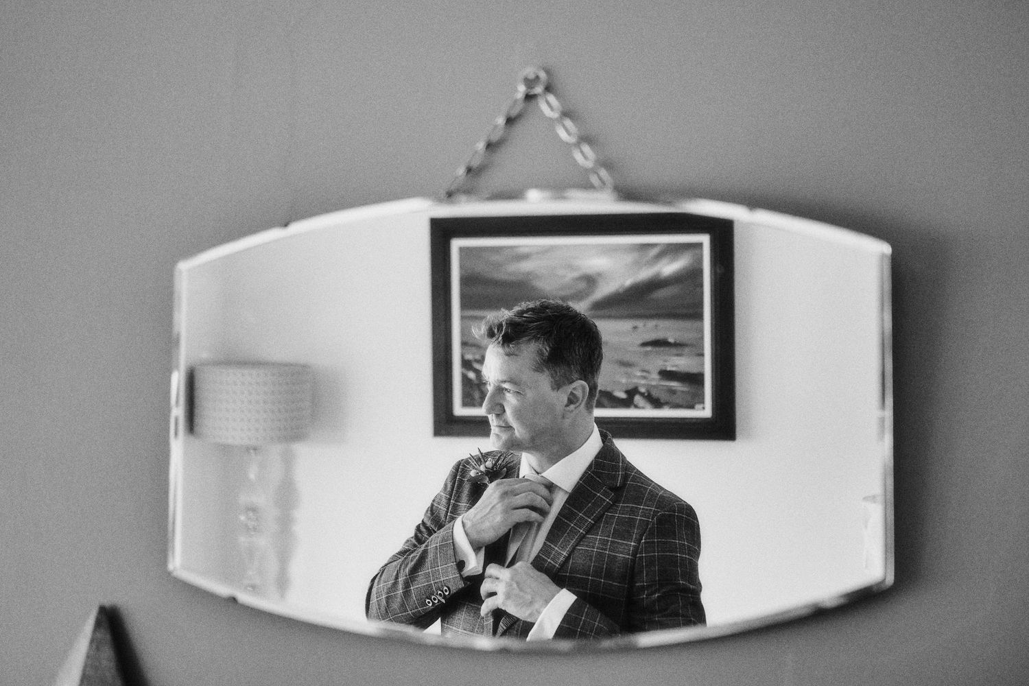 Reflection of Groom adjusting tie on a Glasgow wedding day
