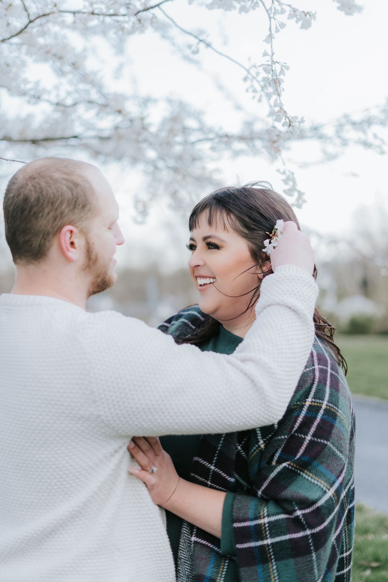 A couple embraces outdoors on a misty winter day wearing cozy sweaters.