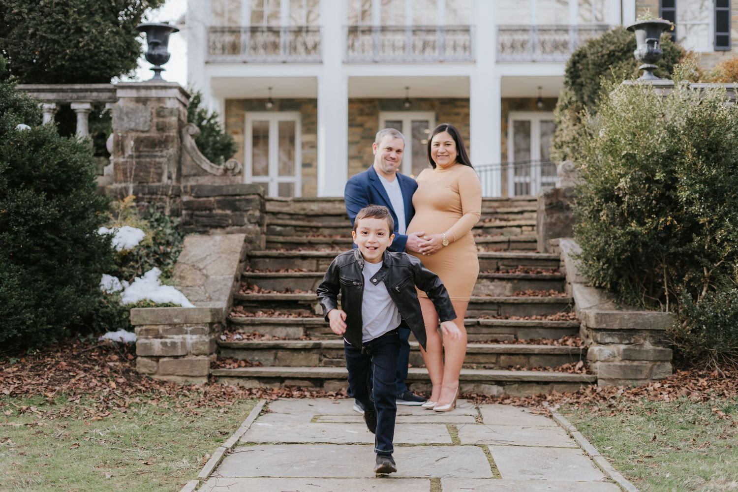 Family portrait on grand stone steps with young child running in foreground.