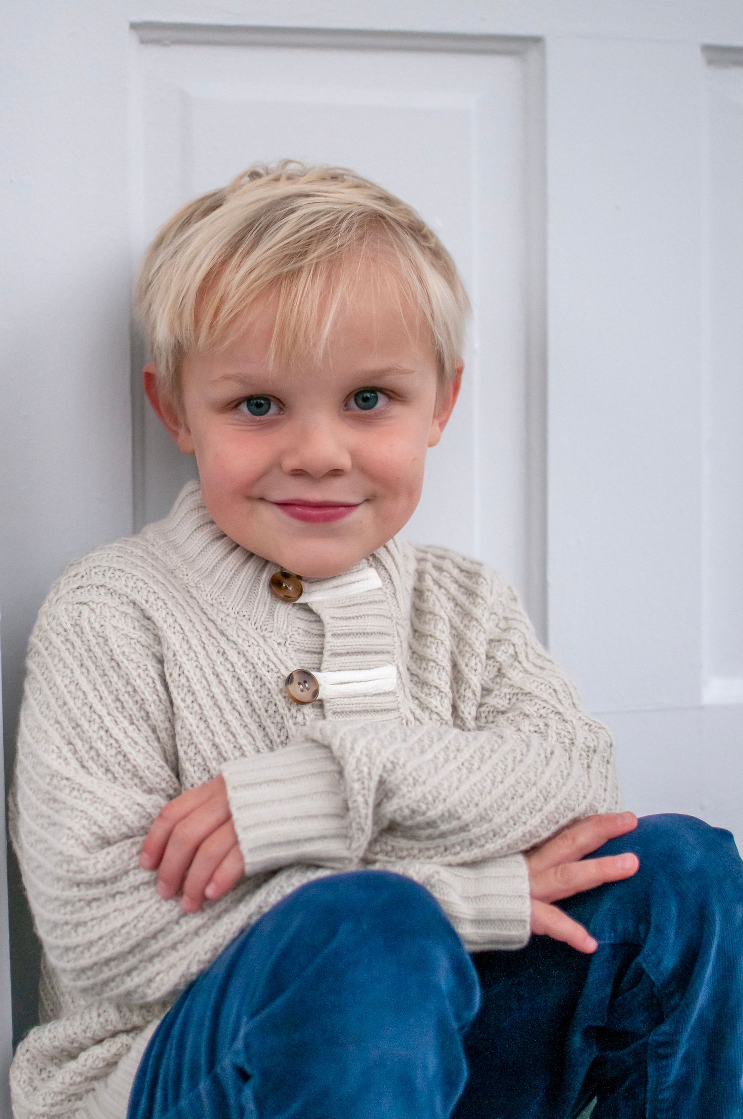 Young boy sitting by white door