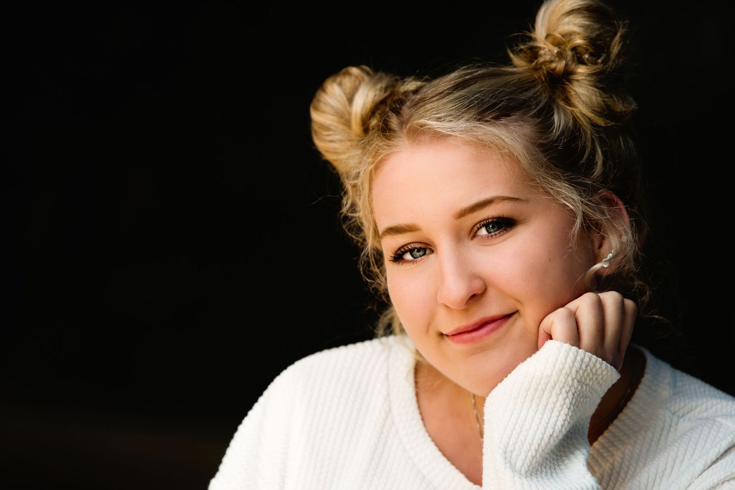 High school senior girl with two buns in hair and hand on chin