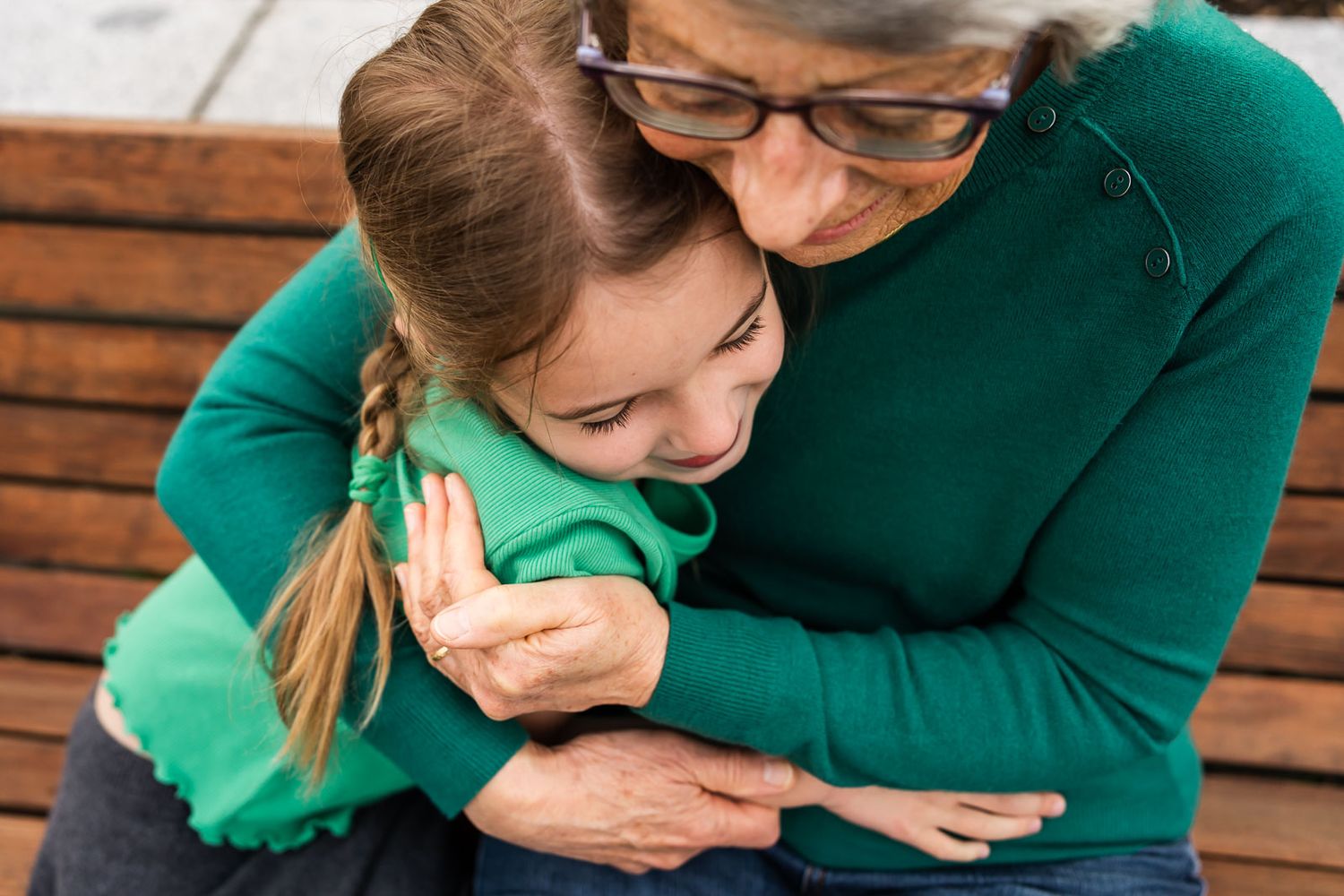 Grandmother seated on a bench, hugging her granddaughter in Kirkland.