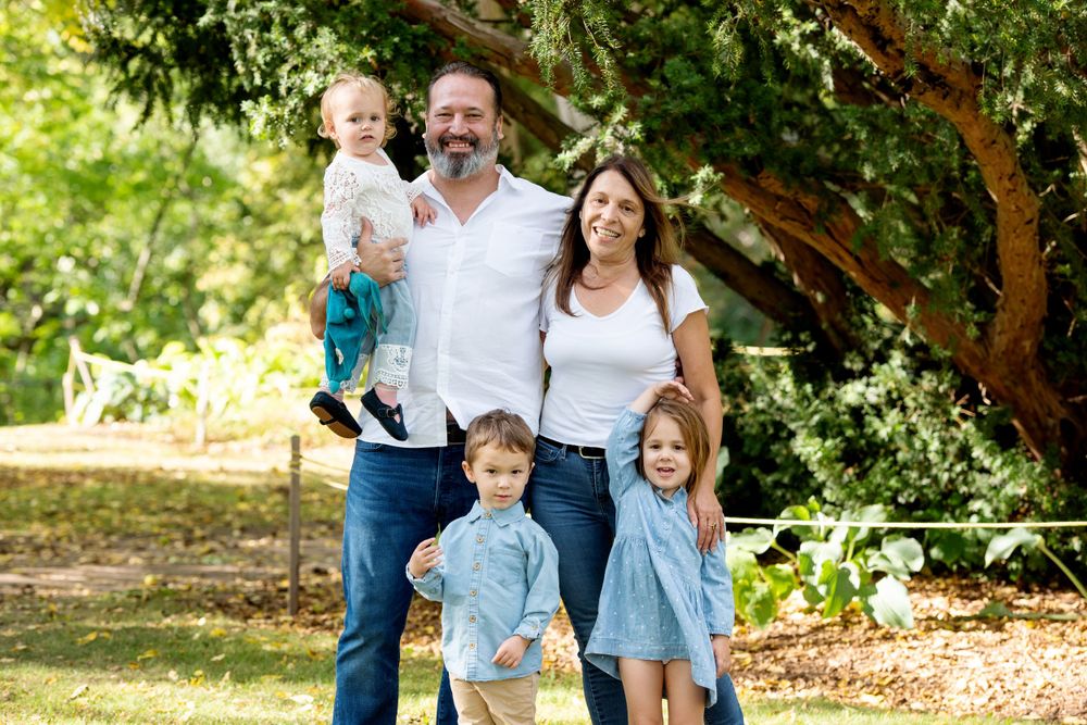 Family group photo outdoors under trees with natural lighting.