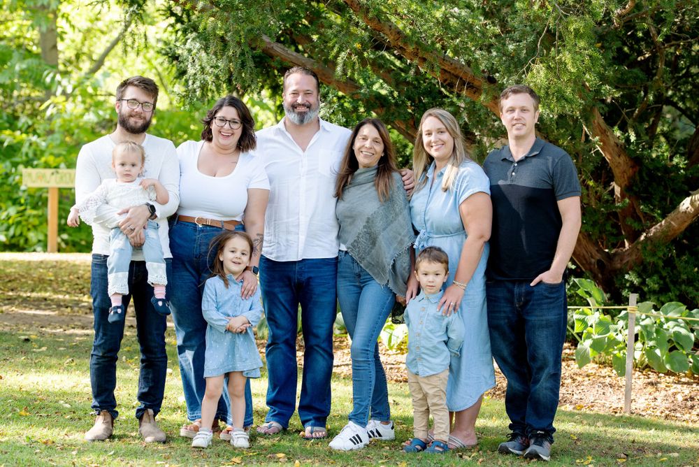 Extended family group portrait in sunny outdoor garden setting.