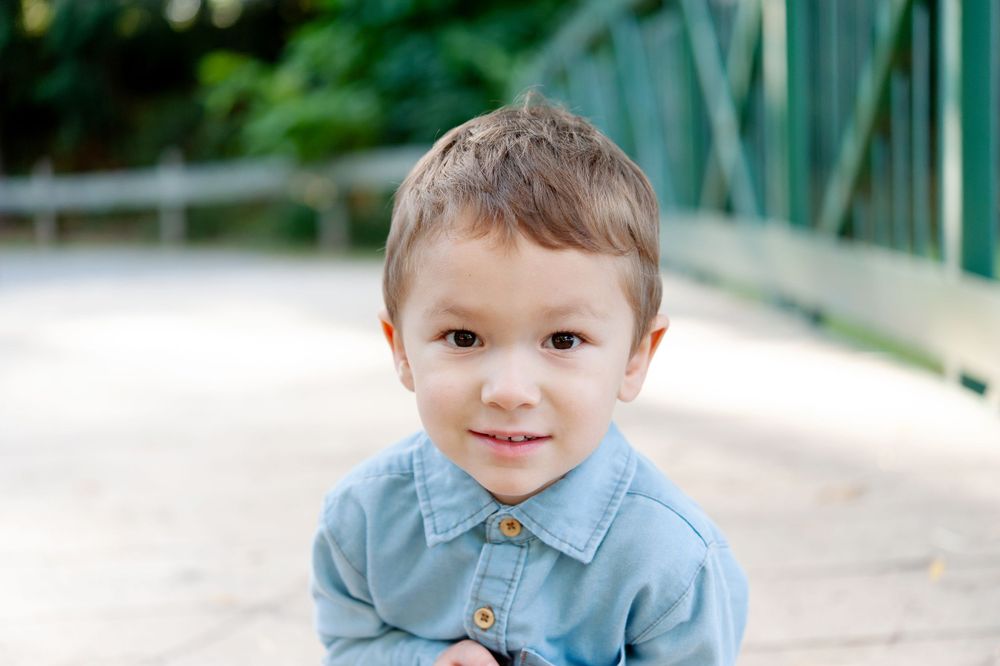 Young child wearing light blue collared shirt smiling at camera.