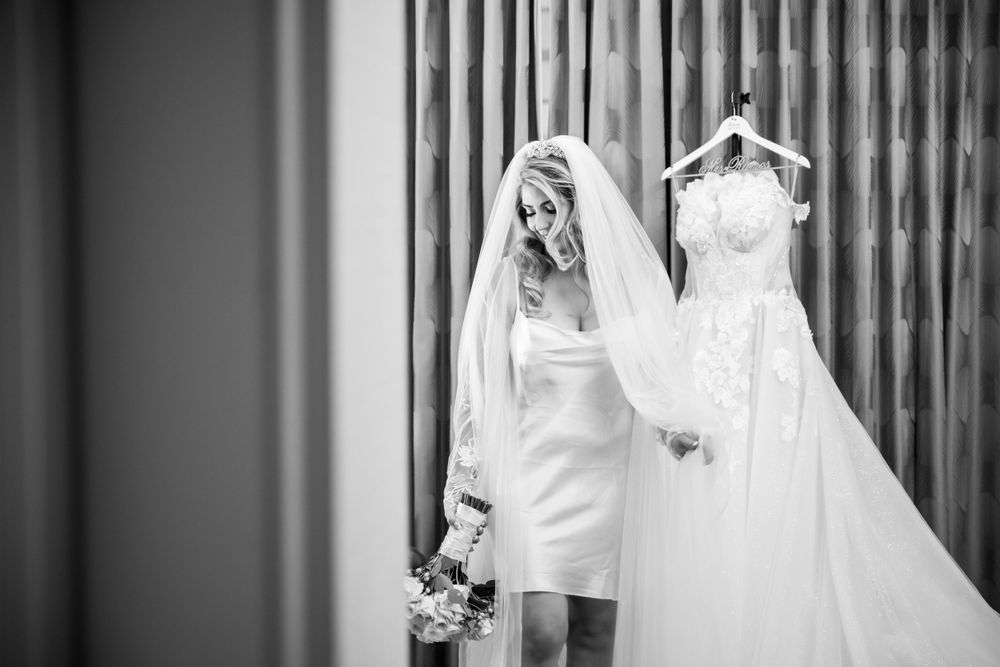 Black and white photo of a short wedding dress with a longer gown hanging beside it.