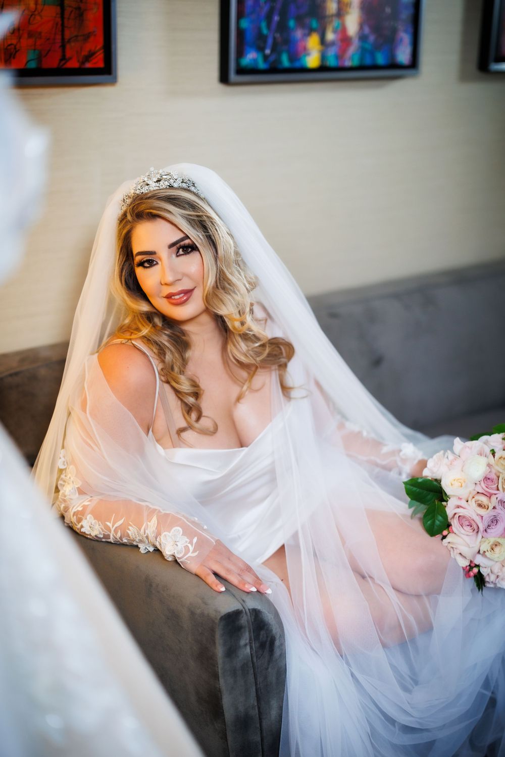 Bridal portrait on a gray couch with soft lighting and colorful artwork in the background.