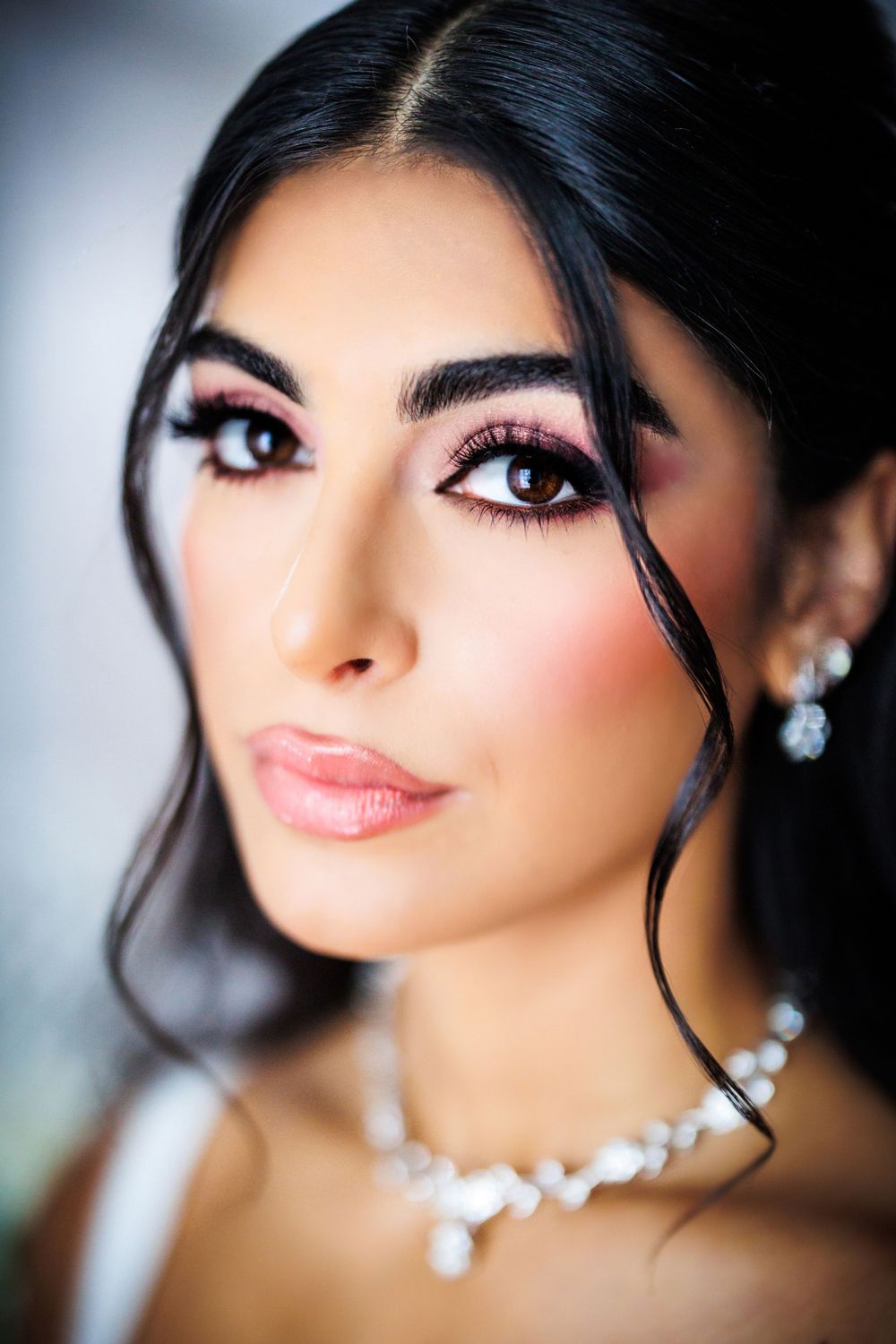 Close up beauty portrait with dramatic makeup, pearl necklace and delicate earrings.