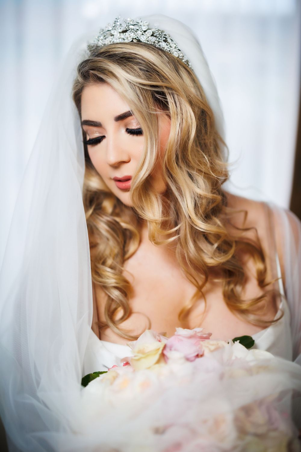 Close-up portrait of bride wearing sparkling tiara and veil with soft romantic lighting.