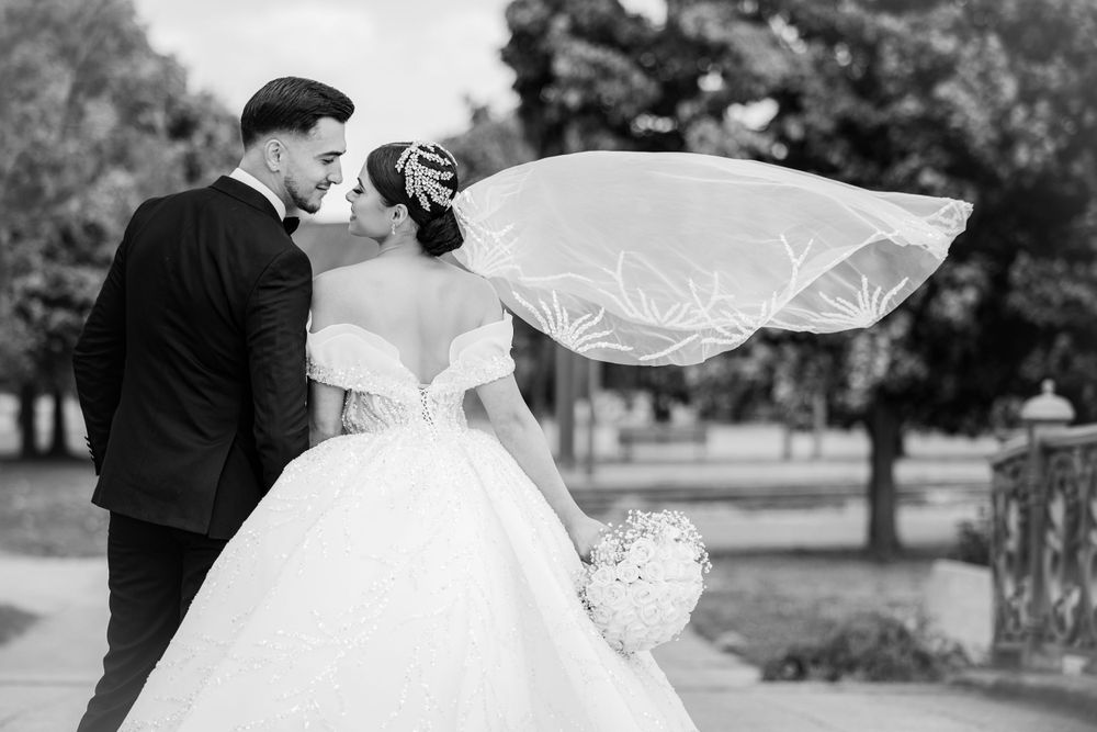 A dramatic black and white photo of a couple with bride's veil flowing in the wind.