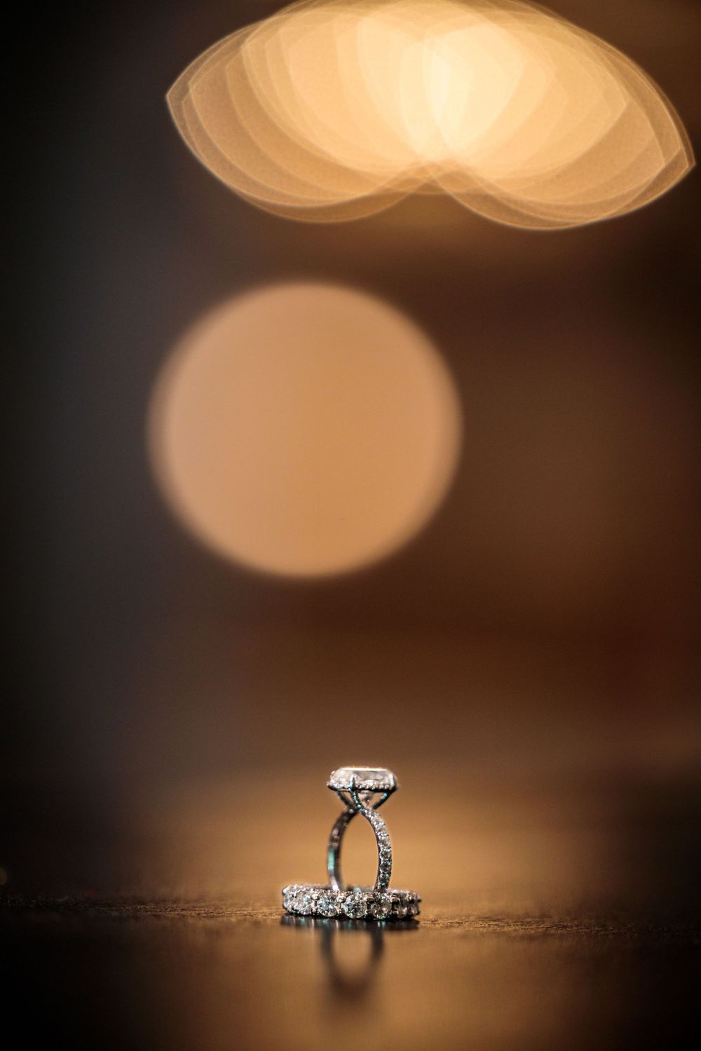 Diamond engagement ring macro shot with artistic bokeh lighting effects in the background.