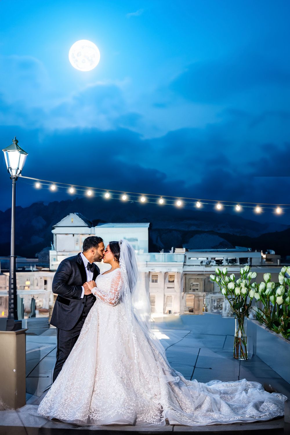 Romantic moonlit rooftop wedding scene with string lights and white floral decorations creating an elegant ambiance.