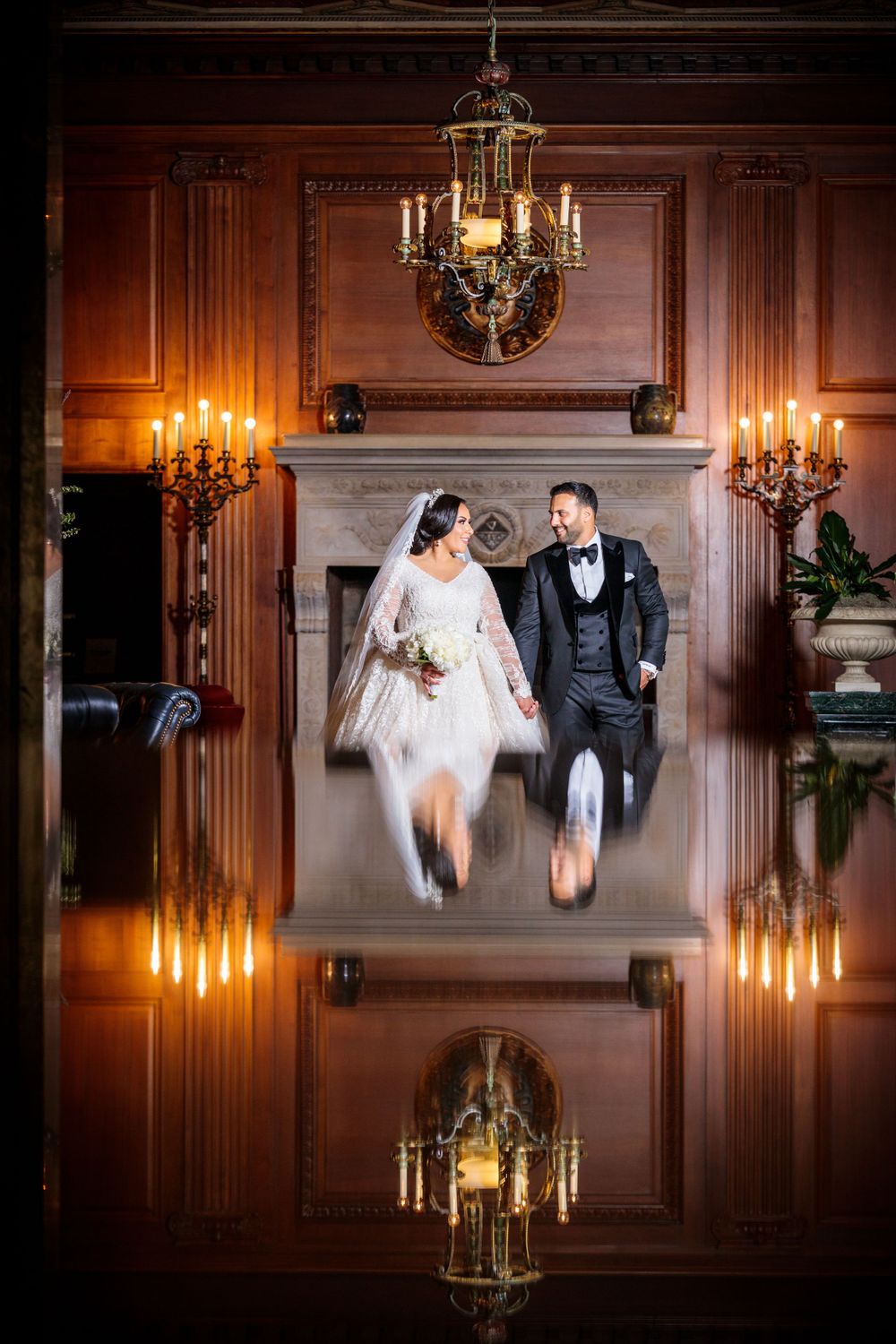 Elegant wedding photo with chandelier and candle reflections creating symmetrical mirror effect.