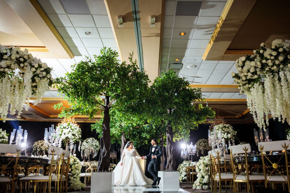 Elegant wedding ceremony setup with a grand tree centerpiece and hanging floral arrangements in an indoor venue.