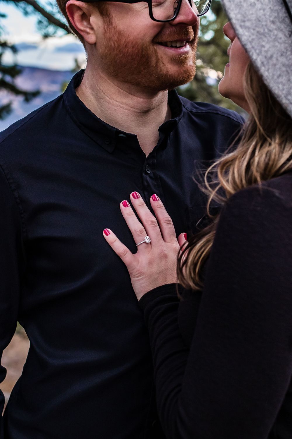 Close-up of engagement ring and pink manicure as couple shares intimate moment outdoors. Colorado engagement photography.