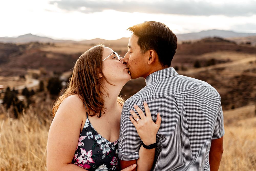 Intimate moment between couple kissing in front of rolling hills at sunset. Fort Collins Engagement Photography.