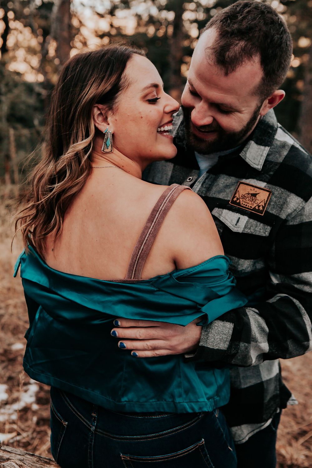 A romantic couple embraces outdoors during golden hour. Colorado engagement photography.