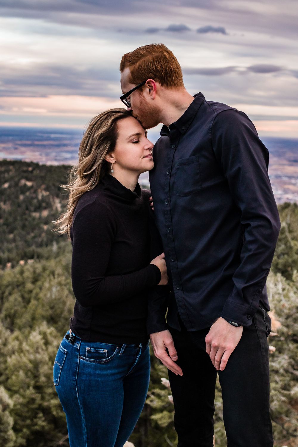 Intimate couple moment captured against scenic mountain vista during sunset. Colorado engagement photography.