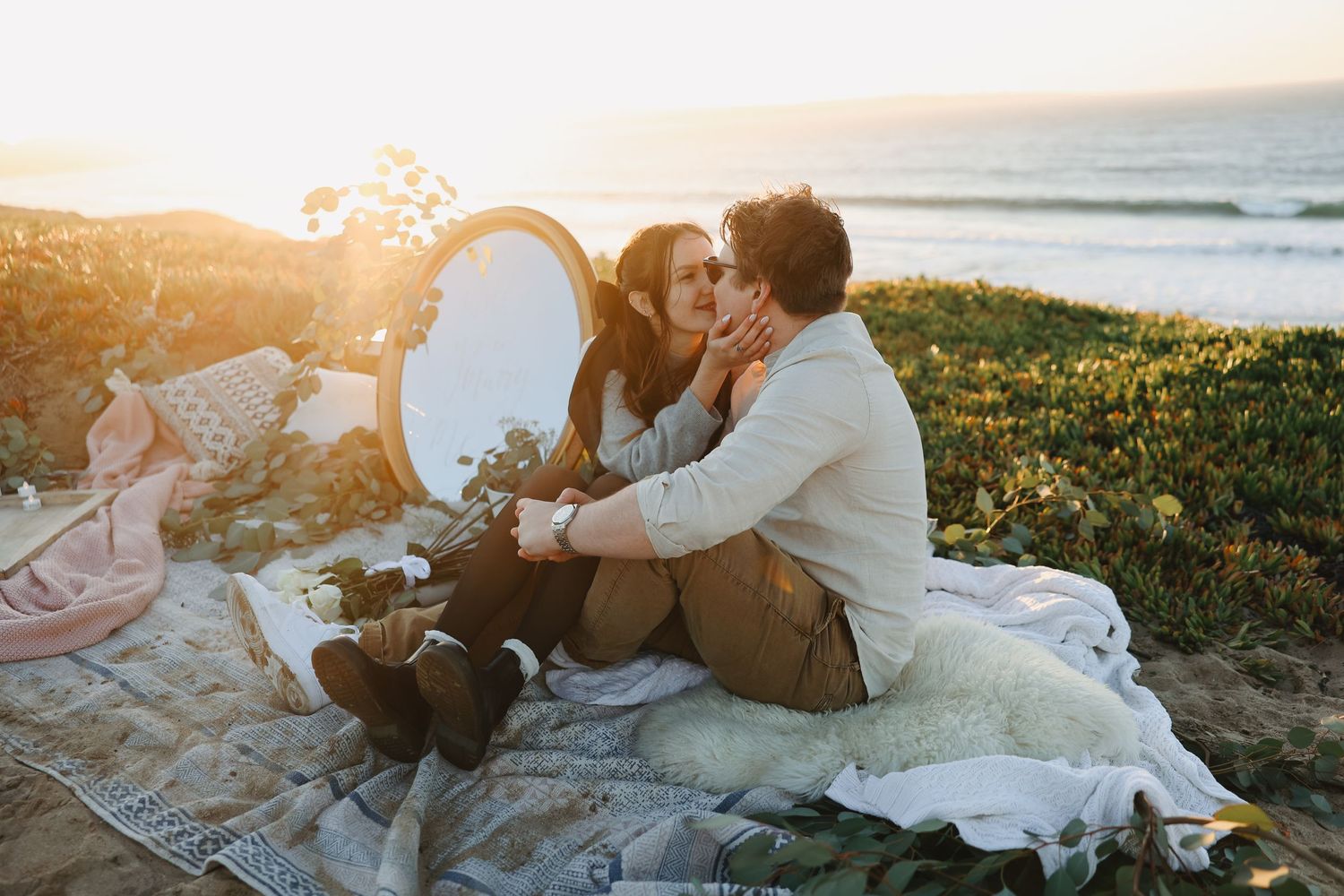 Romantic coastal picnic scene at sunset with couple and vintage decor.