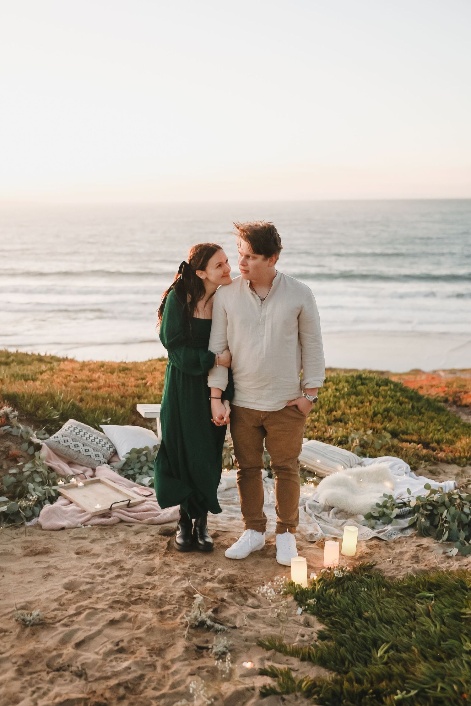 Sunset beach picnic scene with glowing candles and ocean views.