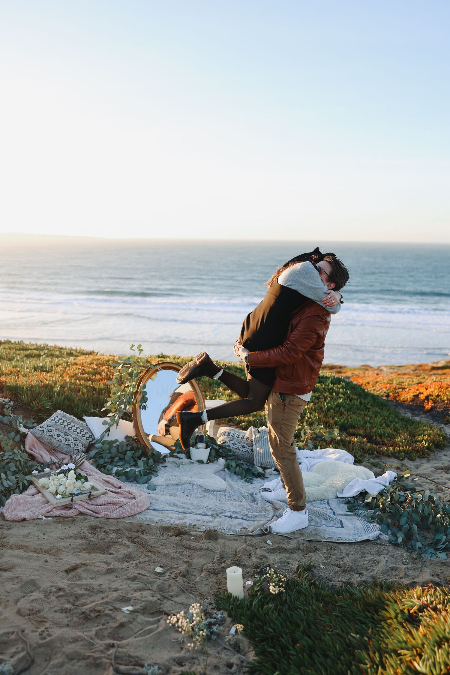 A joyful celebration moment during a seaside proposal with a decorated picnic setting.