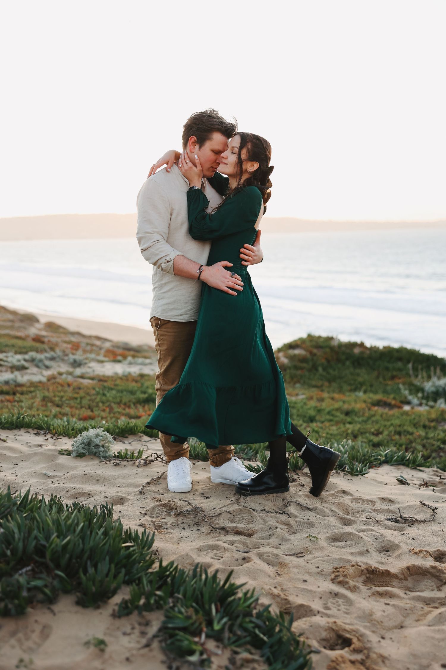 A couple shares an intimate moment on a coastal path during golden hour.